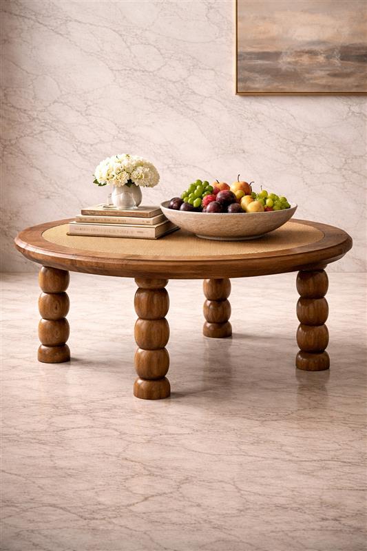 Round wooden table with fruit bowl and flowers.